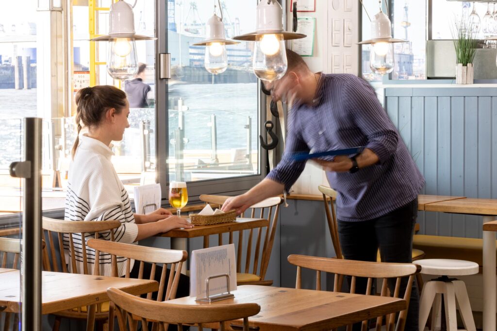 View of the restaurant Fischpfanne with a woman being served by a waiter.